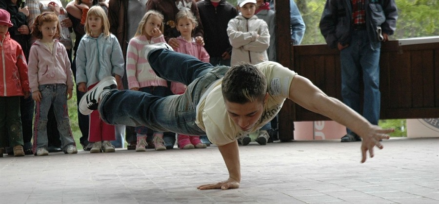 Foto eines Jugendlichen Breakdancers, dem Kinder und Erwachsene zusehen